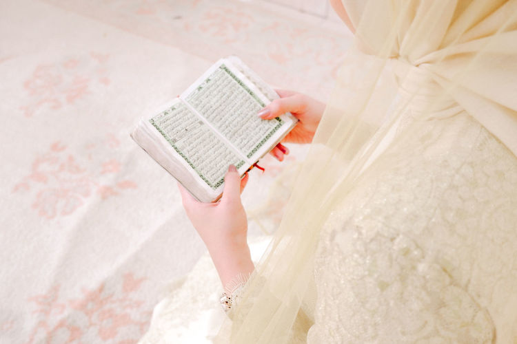 Midsection of woman reading koran