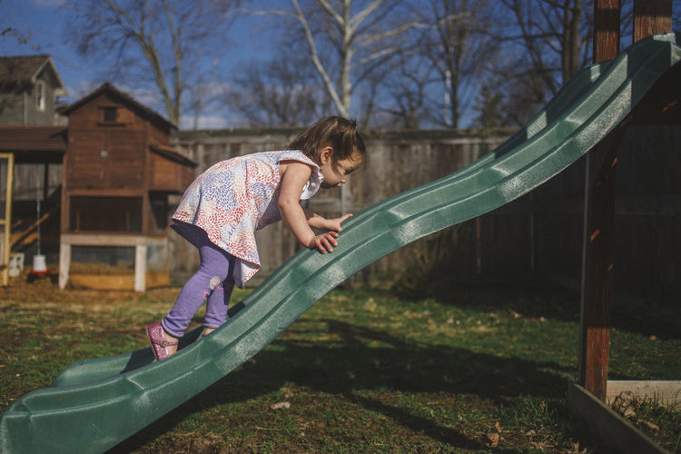 Side view of girl climbing slide at backyard
