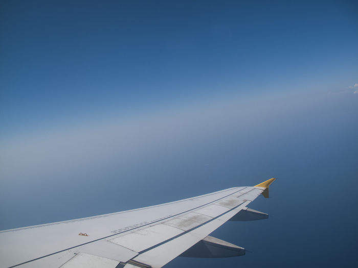 Cropped aircraft wing against blue sky