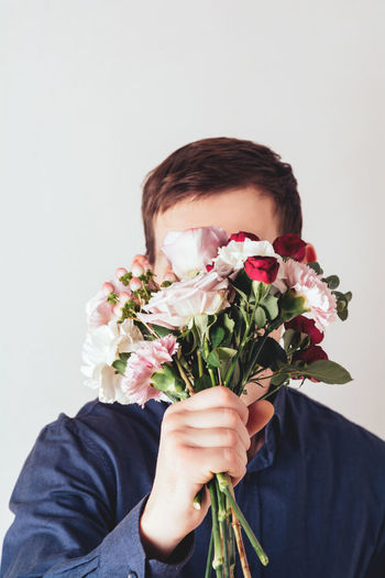 Man  holds a bouquet of flowers in front of his face. birthday, mother's or valentine's day gift
