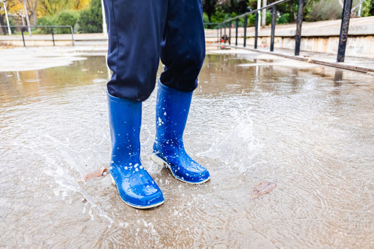 Low section of man wearing boot standing in water