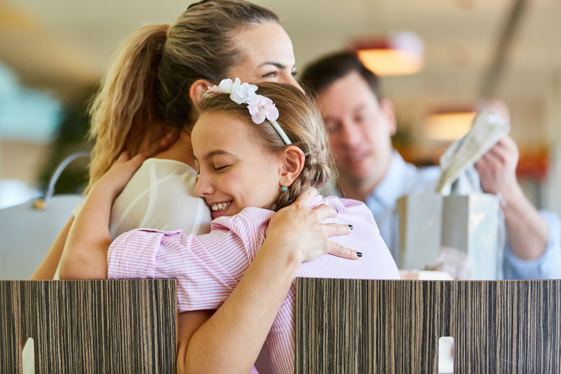 Side view of smiling daughter embracing mother at shopping mall