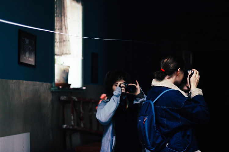 Young man photographing woman using smart phone at home