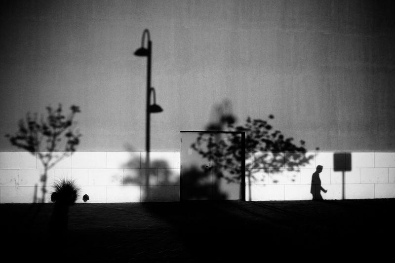 Silhouette of person walking on street against sky