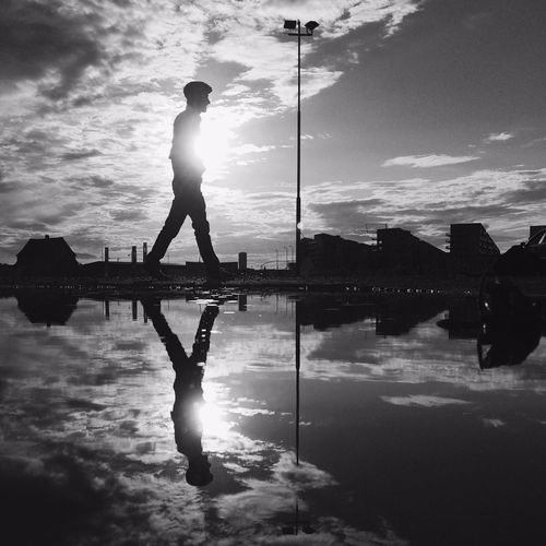 Side view of walking man reflected in puddle