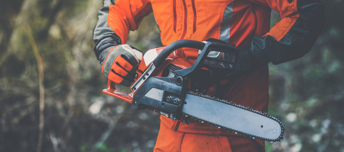 Man holding a chainsaw and cut trees. lumberjack at work gardener working outdoor in the forest.
