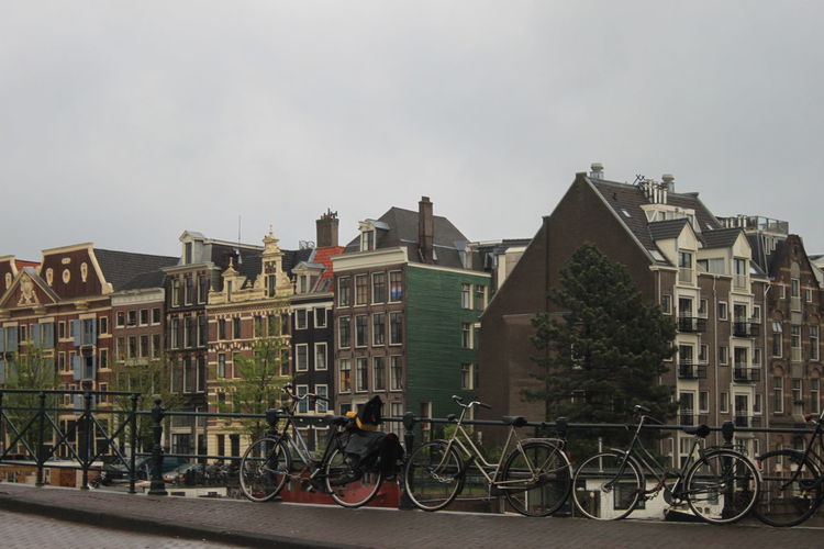 Bicycles on railing against buildings in city