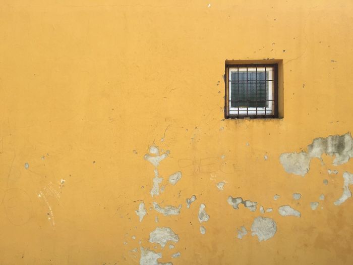 Window on old yellow house wall