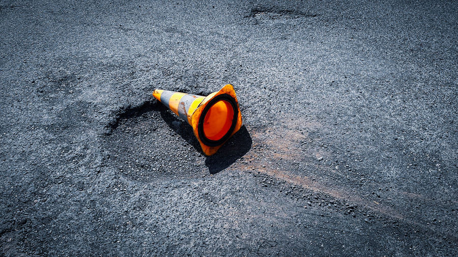 High angle view of orange traffic cone by hole on road