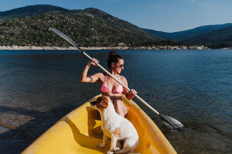 Smiling woman canoeing with dog in lake