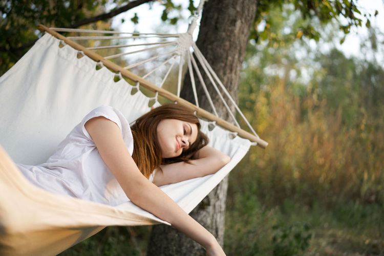 Side view of young woman relaxing on hammock