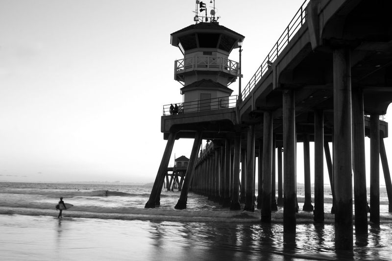 Pier over sea against clear sky in black and white