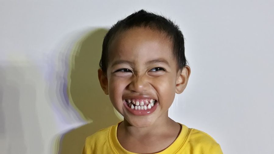 Close-up of smiling boy against wall