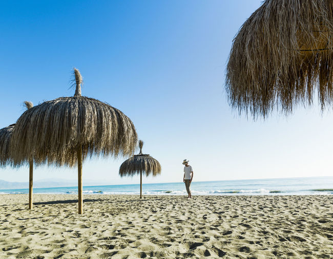 Man walking on the beach sand between umbrellas in alamos beach,