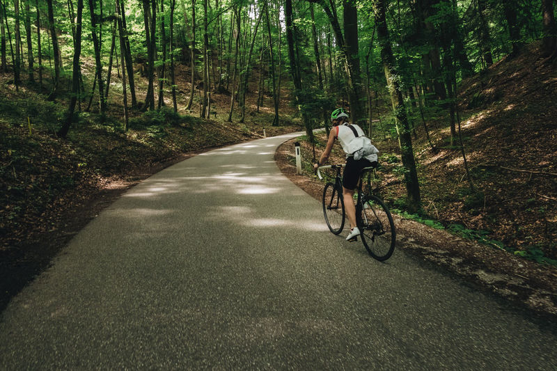 Woman riding her roadbike on road in forest in the austrian alps