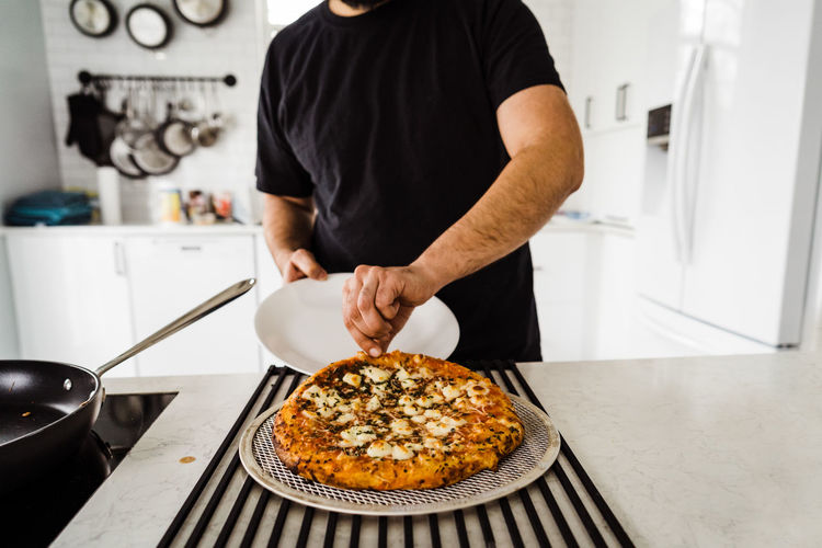 Man transferring fresh cooked pizza to plate