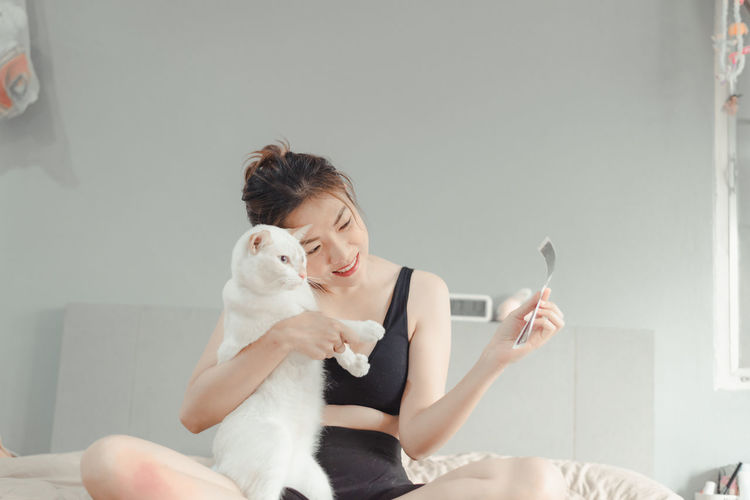 Young woman holding a cat sitting at home