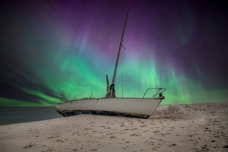 Aurora borealis over a shipwreck off the coast of uttakleiv beach in norway