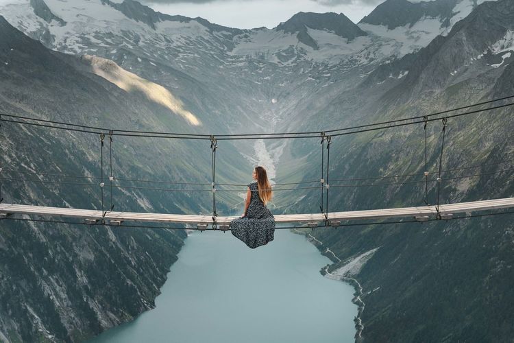 Reflection of woman on railing against mountain range