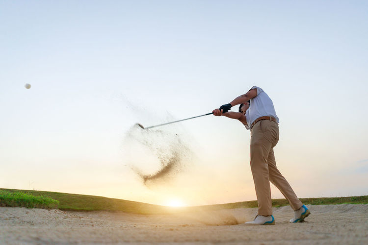 Low angle view of man playing golf against clear sky