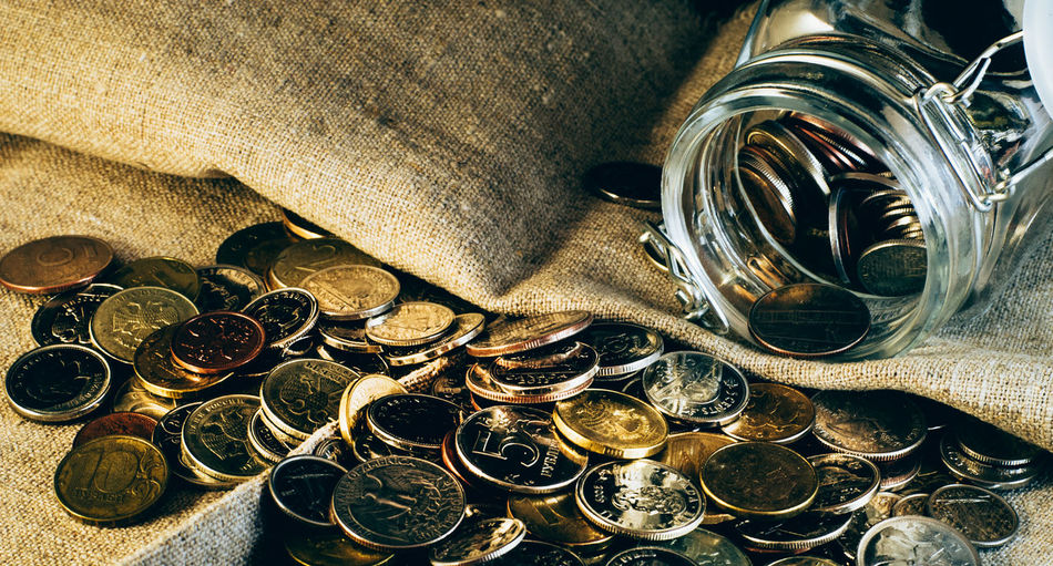 Coins spilling from glass jar on fabric