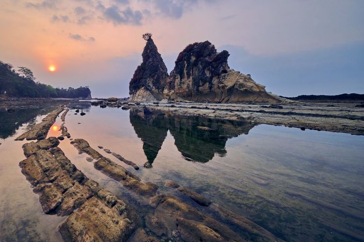 Rock formations in sea against sky during sunset in batu layar, west java