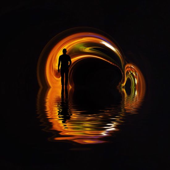 Silhouette man standing in illuminated water at night