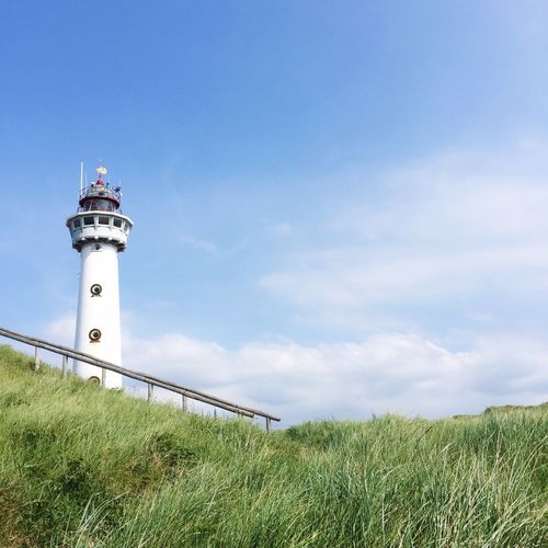 Low angle view of lighthouse by field against sky at egmond aan zee