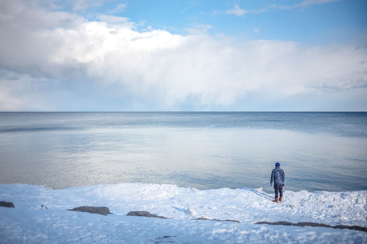 Man on sea against sky during winter