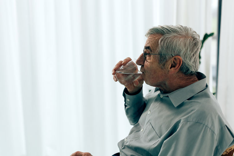 Senior man pensioner drinking a glass of water. healthy habits lifestyle concept for older people.
