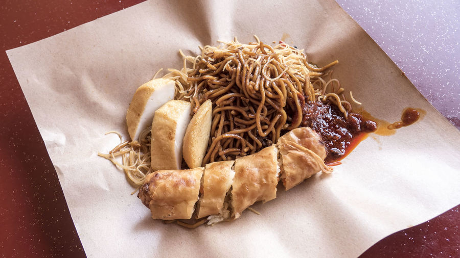 High angle view of spring rolls with noodles on paper at table