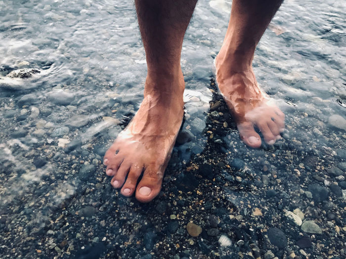 Low section of man standing in water
