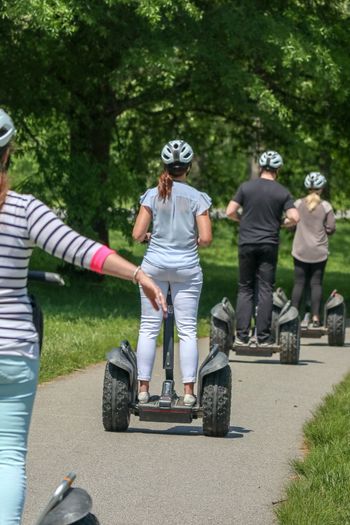 Rear view of people riding segway in park