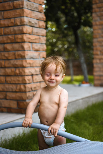 Little boy laughing in the yard of a house on the street in diapers