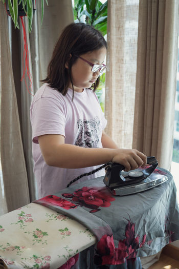 Girl ironing dress at home