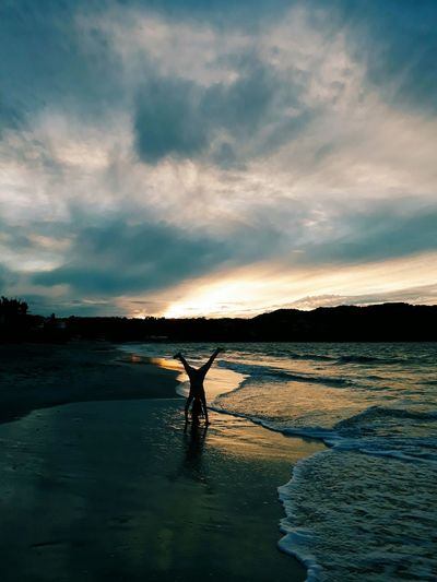 Silhouette man standing on beach against sky during sunset