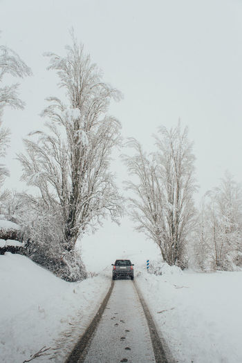 Modern automobile driving on straight empty road covered with snow on cold winter day in countryside in foggy weather
