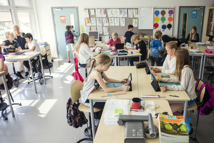 High school students sitting with teacher in classroom