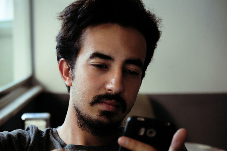 Close-up portrait of young man using smart phone