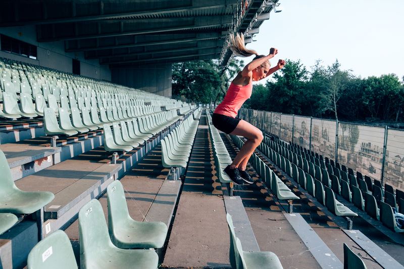 Side view of fit and healthy woman workingout at the stadium jumping up and down the steps