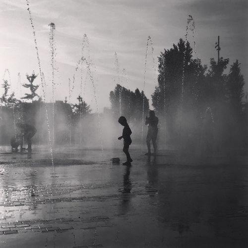 People playing in fountain at park