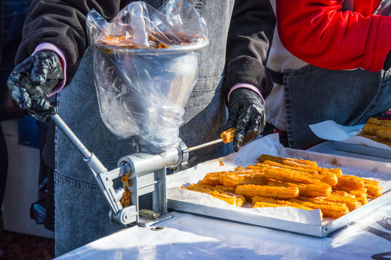 Midsection of person preparing churros on table