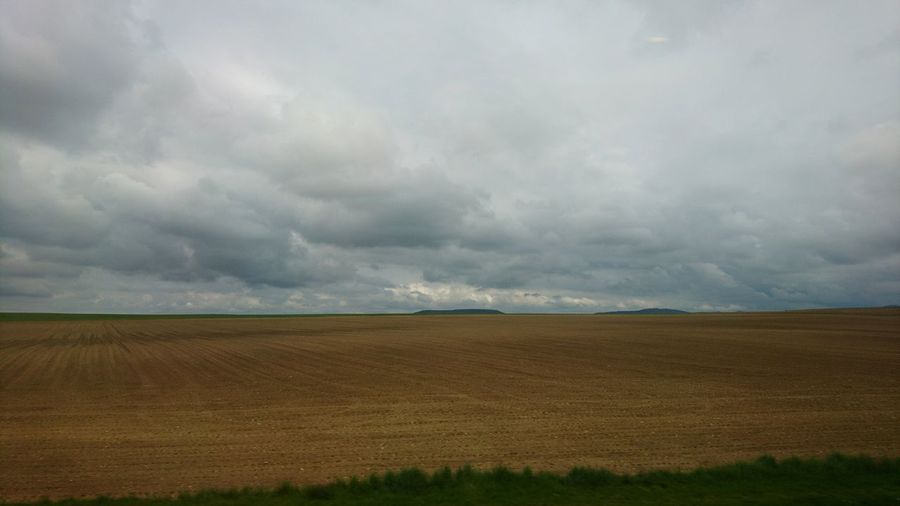 Scenic view of field against cloudy sky