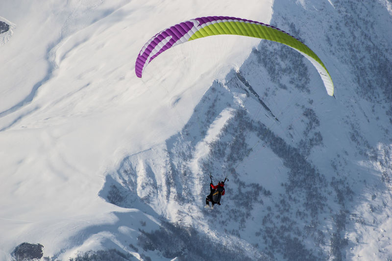 Person paragliding against snowcapped mountain