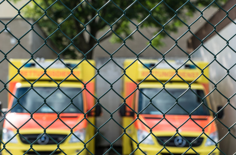 Full frame shot of chainlink fence against ambulances