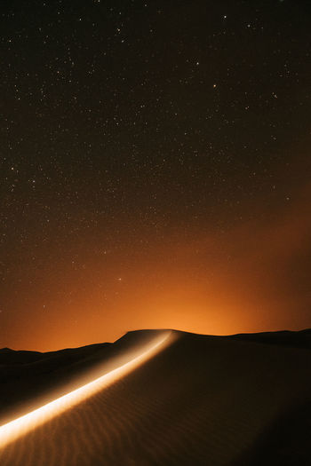 Scenic view of landscape against sky at night in the desert full of stars