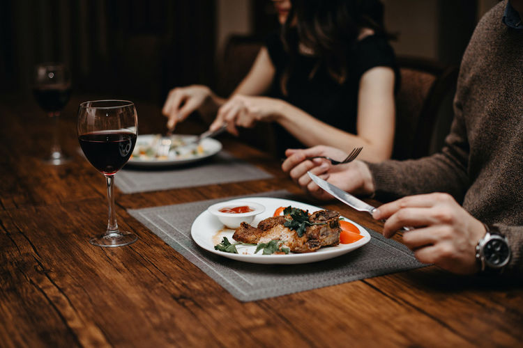 Midsection of man and woman having food in restaurant