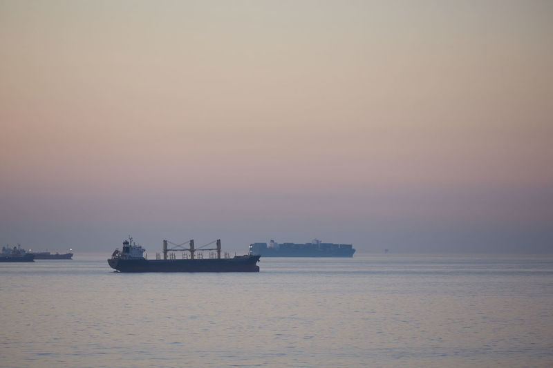 Boat sailing in sea against clear sky during sunset