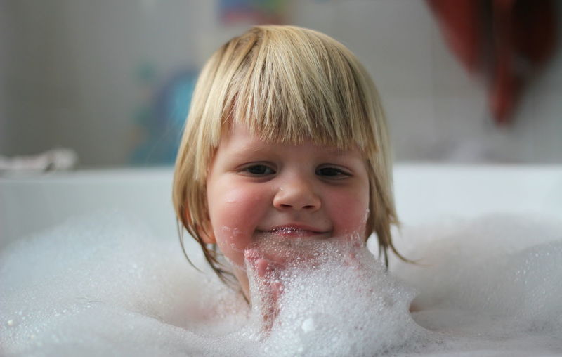 Close-up portrait of a smiling boy in bathtub