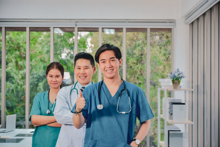 Portrait of smiling doctors gesturing while standing at hospital